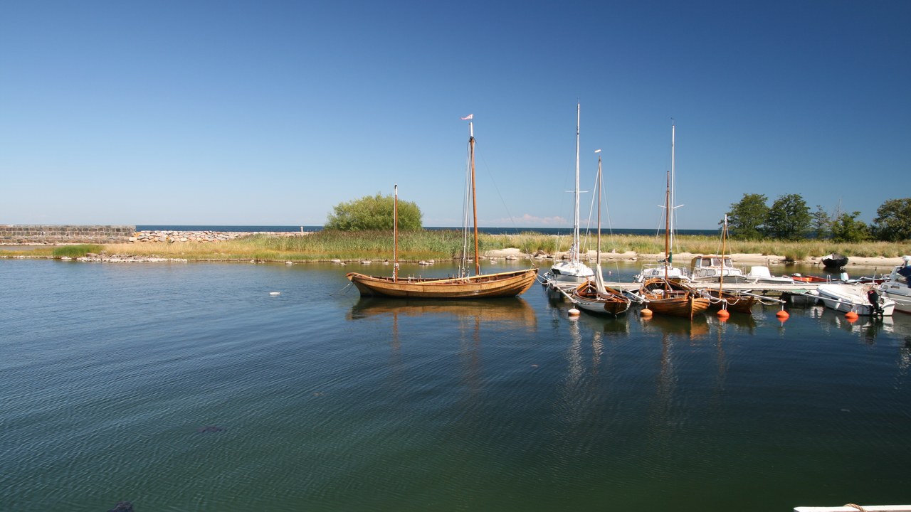 Hamnen i Kivik med låga byggnader och havet i bakgrunden.